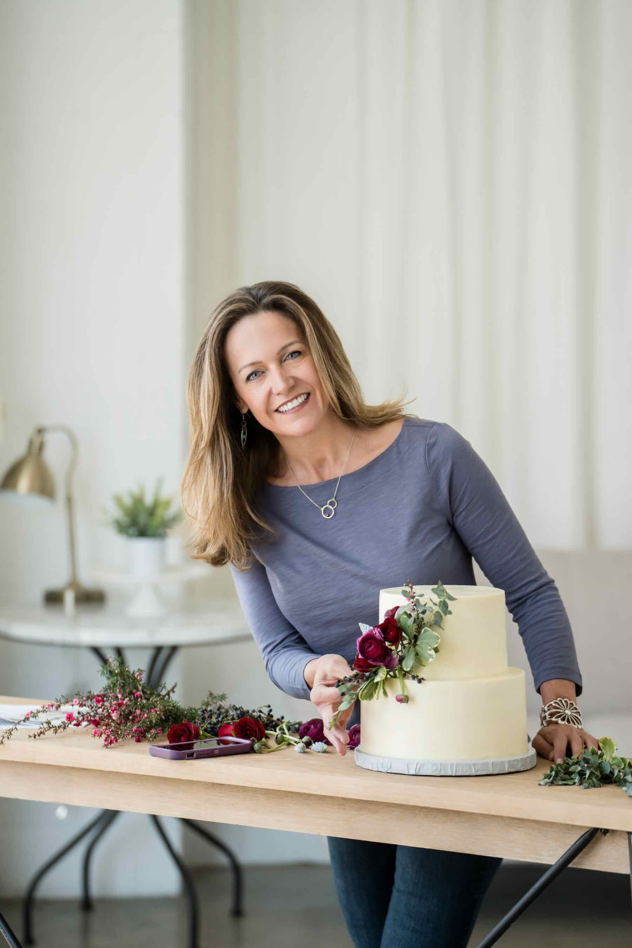 Wendee Vezzetti arranging flowers on a two-tier wedding cake