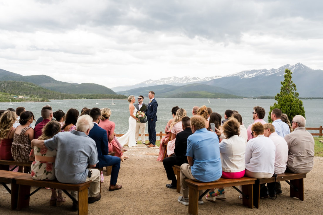 Guests standing around a lakeside Colorado wedding ceremony