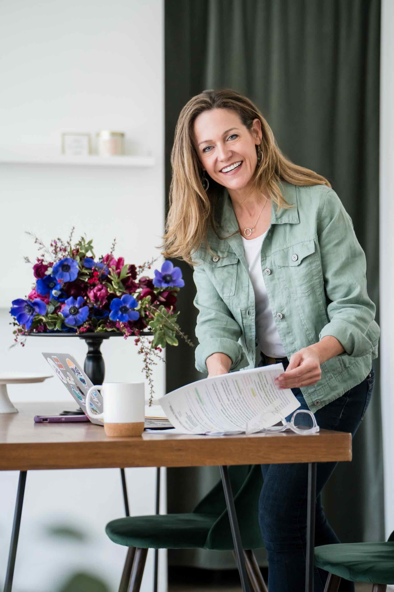 Wendee Vezzetti smiling, holding a printed wedding plan at her desk